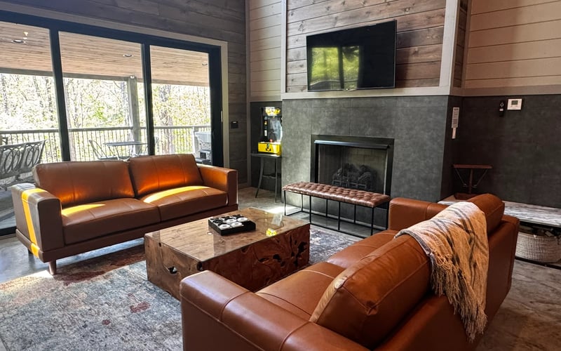 Rowdy Creek living room with leather sofas, fireplace, and floor-to-ceiling windows.