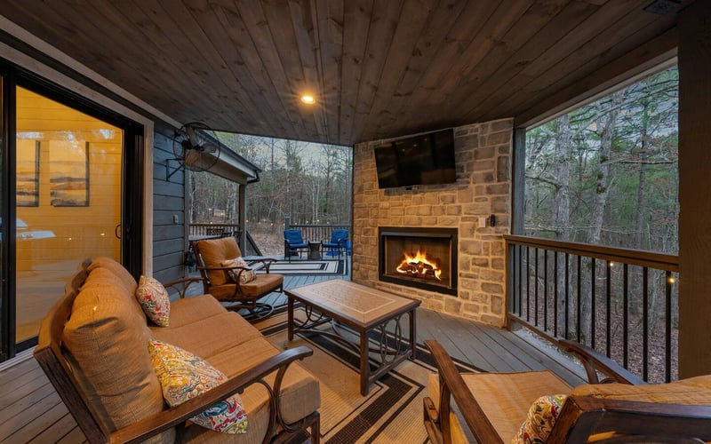 Rowdy Creek covered porch with outdoor fireplace, TV, and seating area.